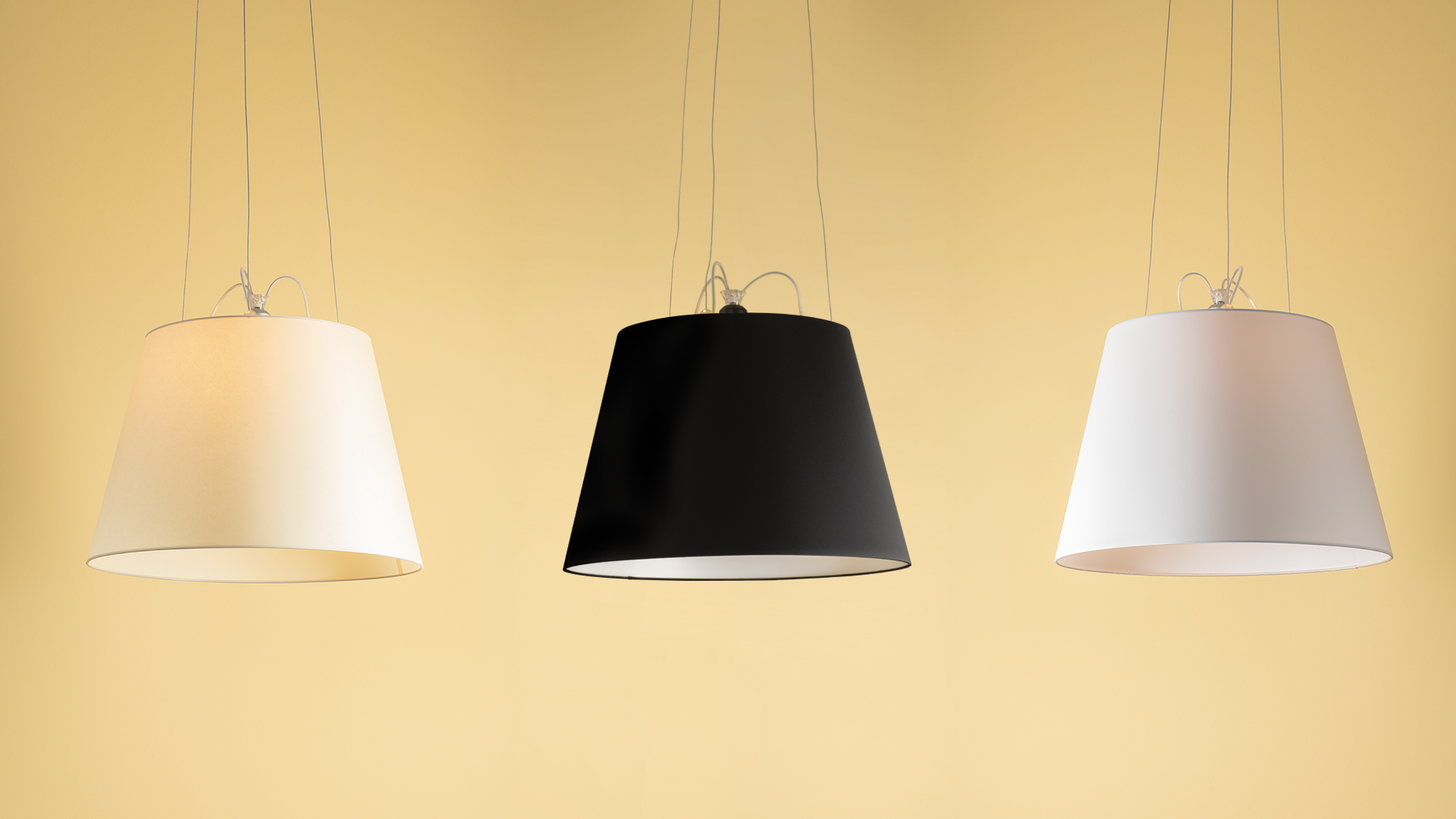 Three Artemide Tolomeo Mega Sospensione pendant lamps: two white and one black, with tapered fabric shades on thin cables