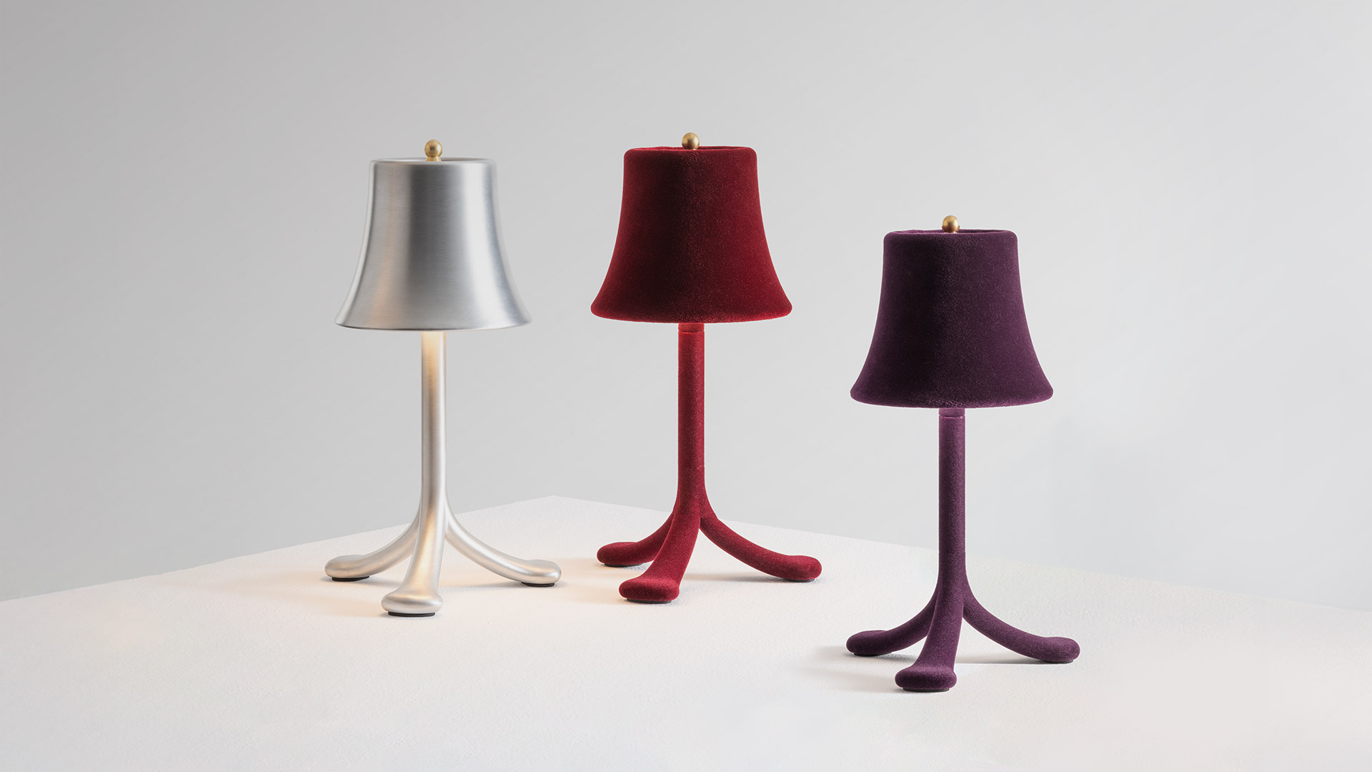 Trois Rois table lamp by Artemide: close-up of brushed aluminum shade with gold finial, and hand holding portable version with flexible stem