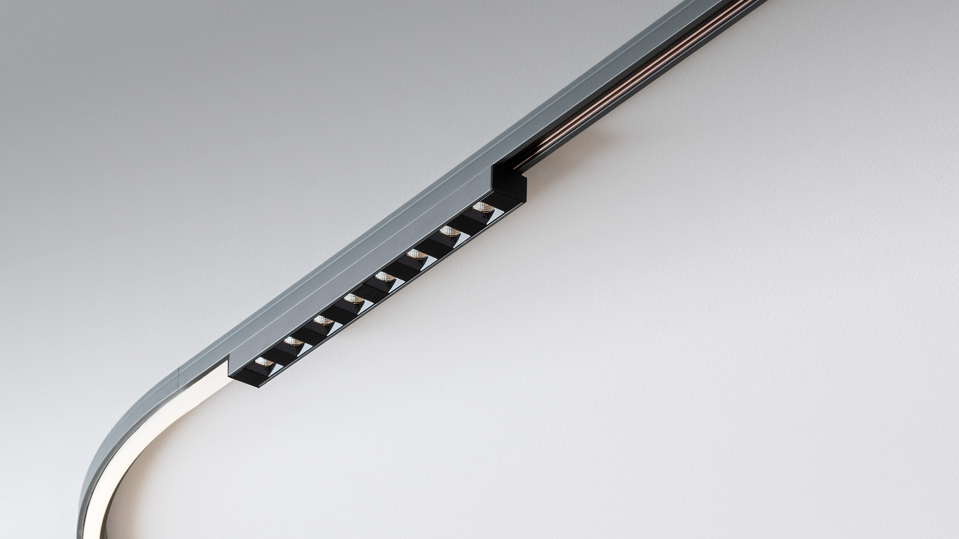 Artemide Turn Around System: adjustable cylindrical LED spotlights in grey mounted on ceiling and floor tracks, emitting warm light
