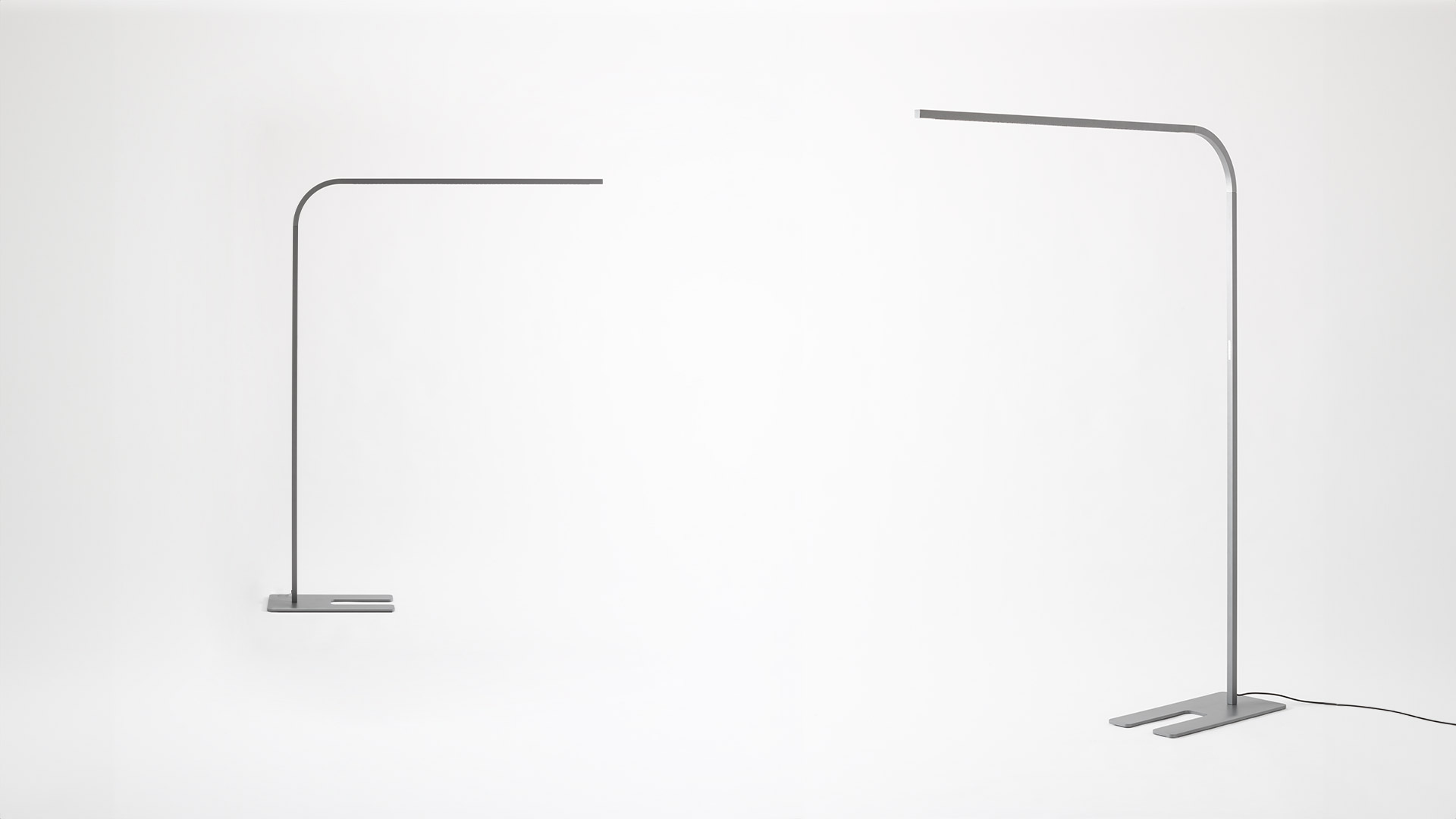 Artemide Turn Around Floor lamp in white beside a minimalist desk with laptop, illuminating a clean home office workspace