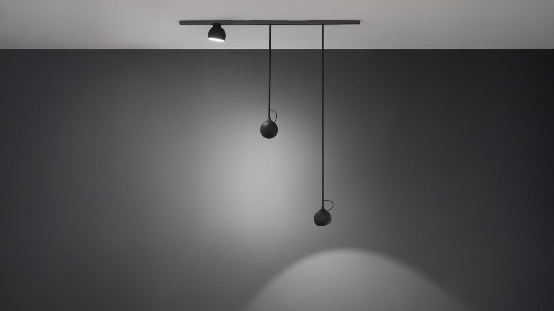 Artemide Turn Around System: black track on ceiling with one spotlight and two spherical pendant heads hanging at different lengths