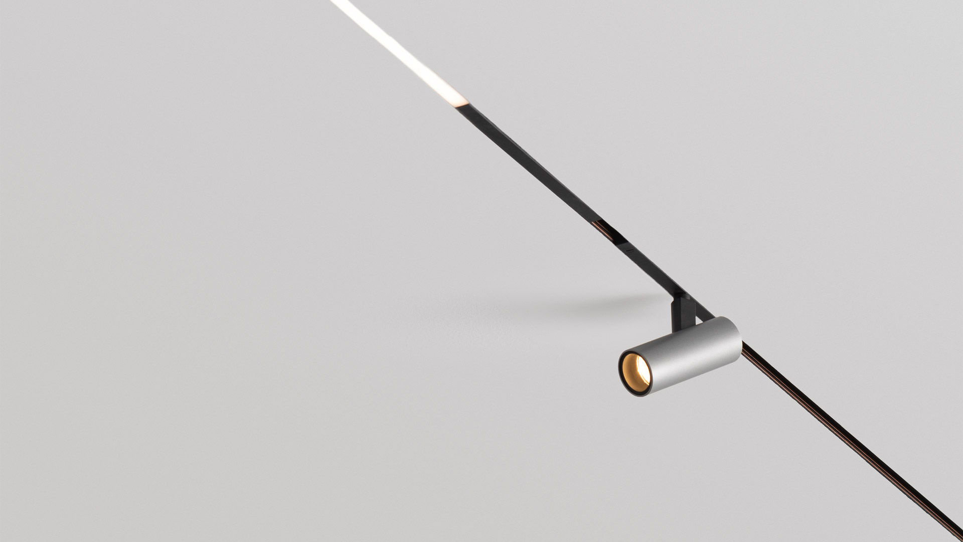 Six Artemide Turn Around System pendant lights on a rail: tilting spherical shades in white, dark blue, and one yellow, hanging at varying lengths.
