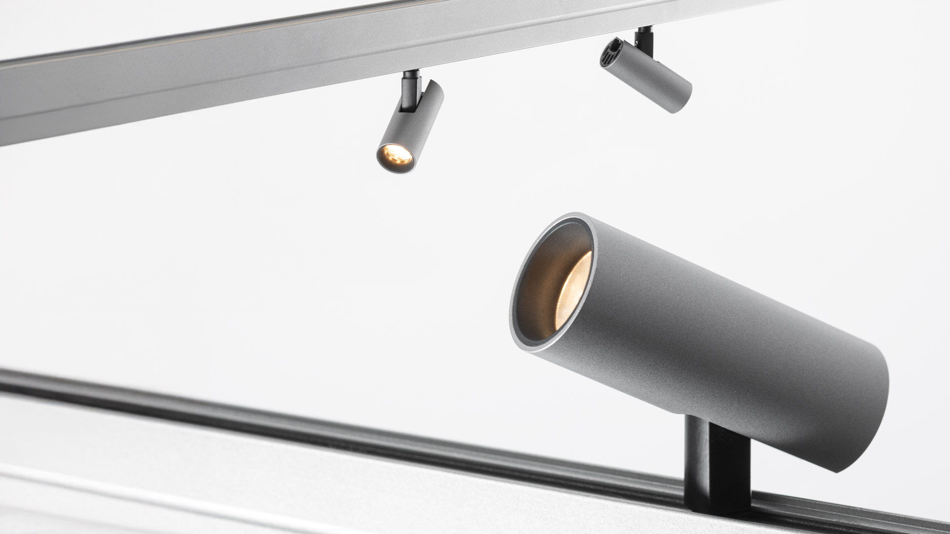 Artemide Turn Around System: cylindrical silver spotlight on a diagonal black track, with warm gold inner reflector