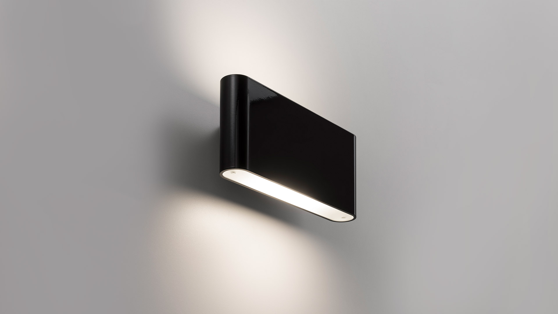 Artemide Two Flags Parete black wall lamp emitting warm light upward and downward against a grey wall