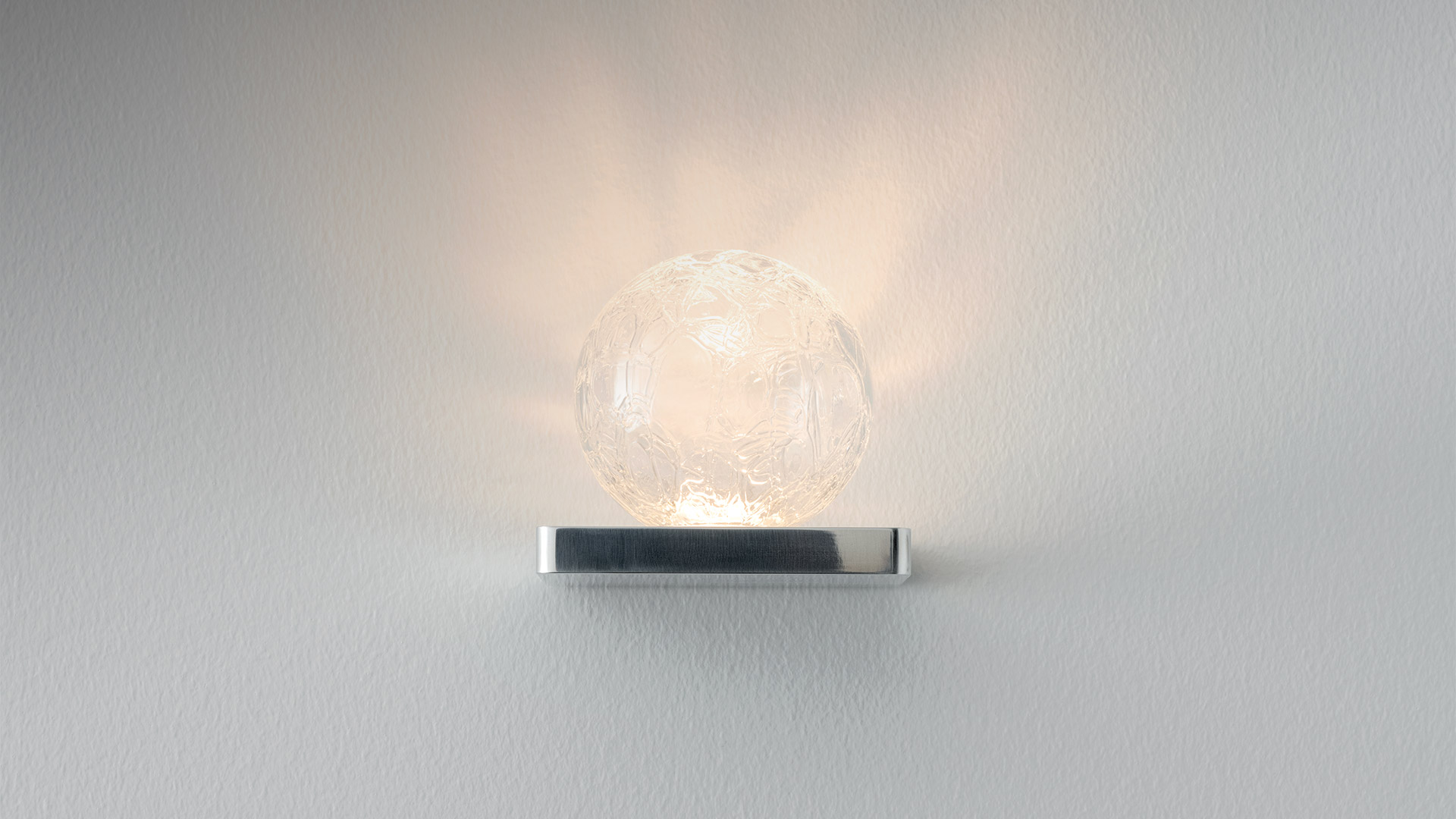 Artemide Ulrich und Diotima wall lamp: textured glass sphere on a polished chrome rectangular base, emitting warm diffused light