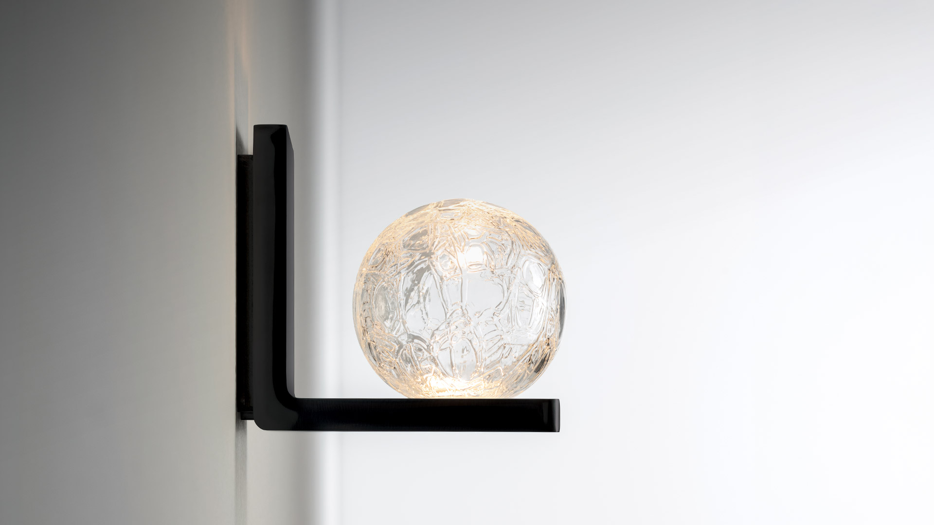 Artemide Ulrich und Diotima wall sconce with textured glass sphere diffuser on chrome rectangular backplate, emitting warm light
