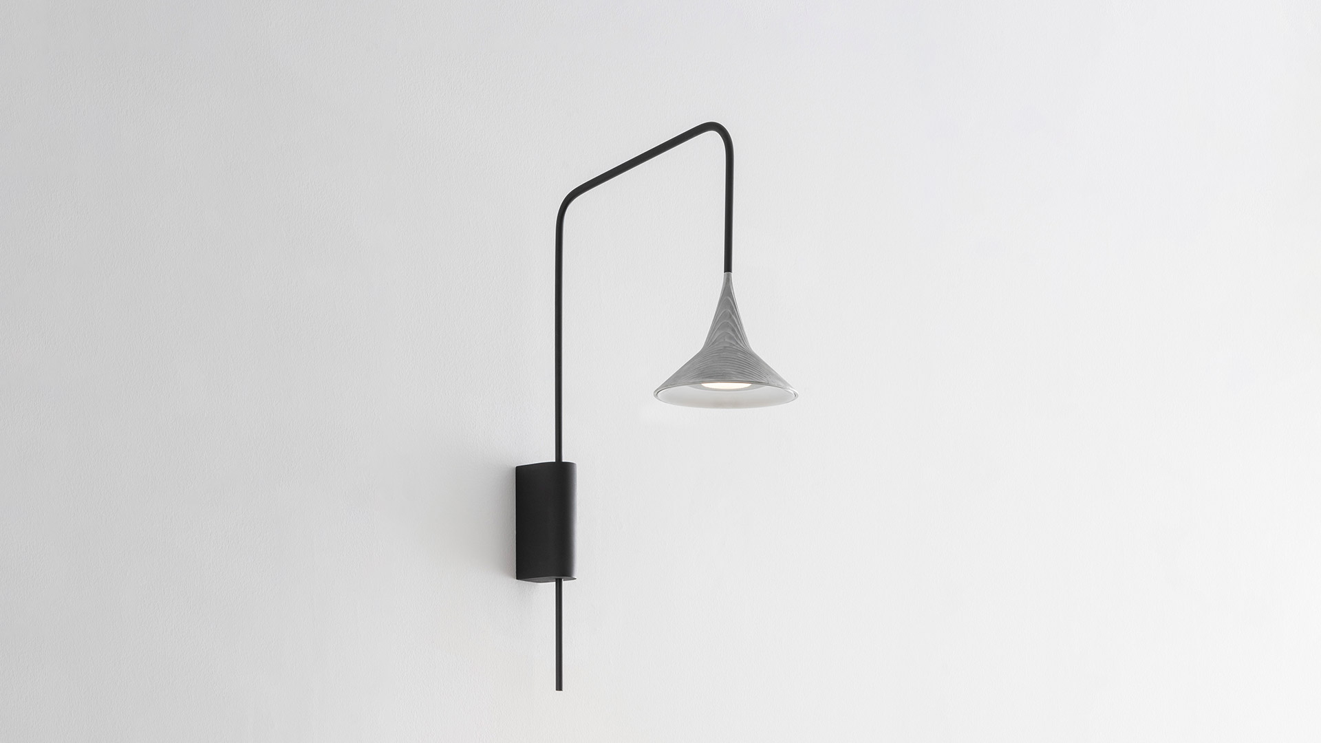Artemide Unterlinden Outdoor wall lamp: black metal arm extending from wall mount, with a conical aluminum shade hanging at the end
