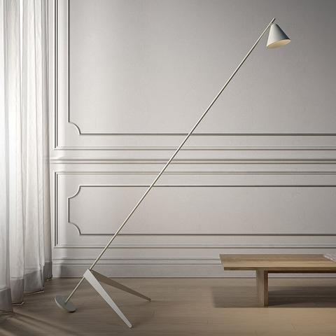Artemide Vea floor lamp: slim diagonal white stem with conical shade, tripod base, in a classic white paneled room with low wooden table
