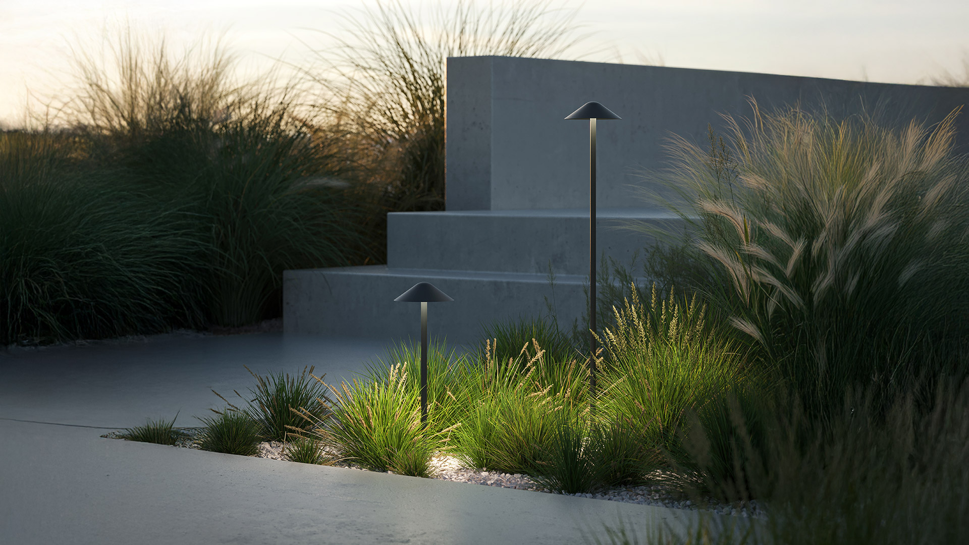 Two Artemide Vea Bollard outdoor path lights with dark conical shades illuminate ornamental grasses in a minimalist garden at dusk