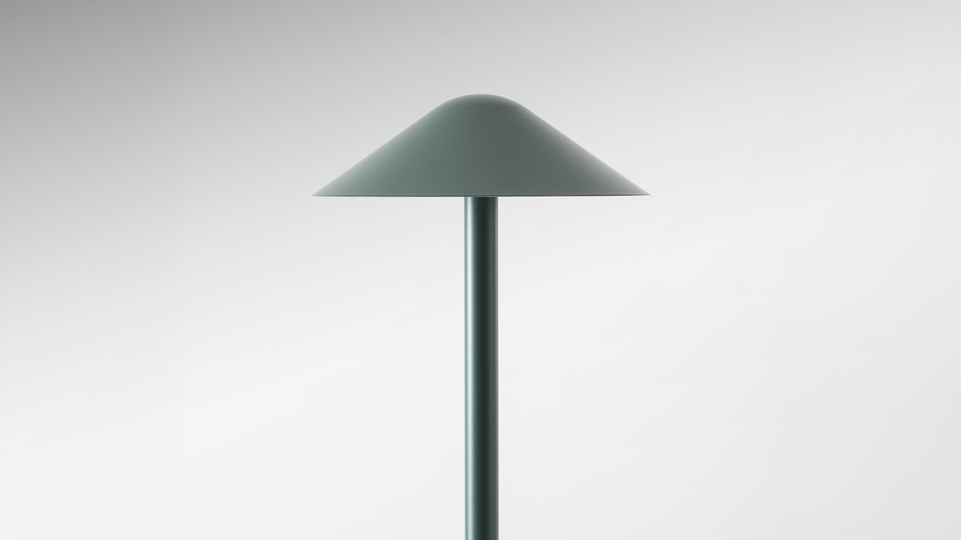 Two Artemide Vea portable lamps in dark green, conical shade design: small table version and tall floor/bollard version, both casting warm light downward