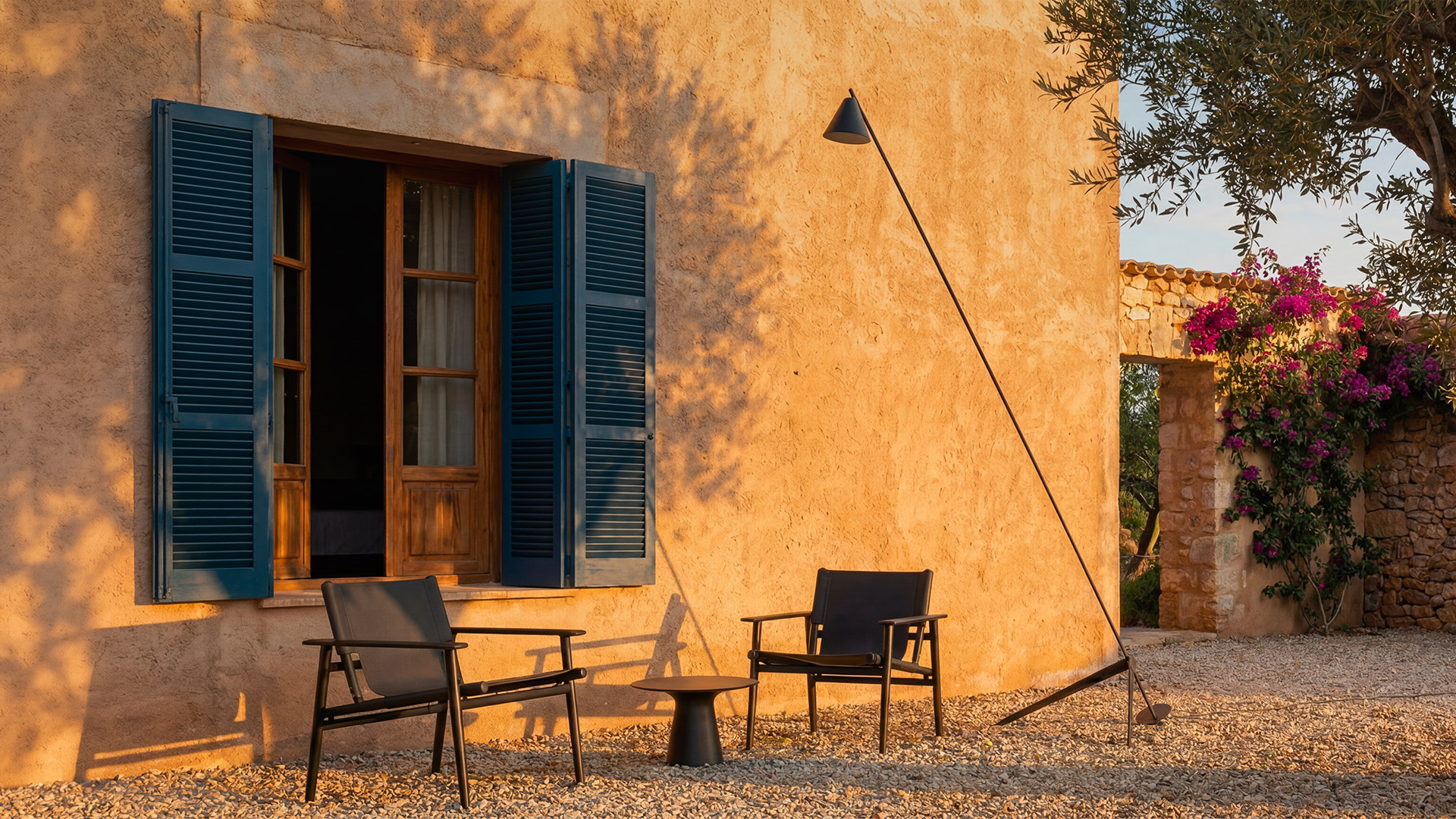 Aerial view of person reading on wooden bench in garden, next to a tall slim Artemide Vea floor lamp on grass