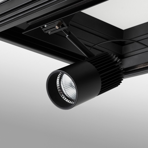 Artemide Vector track spotlight in matte black, mounted on Vector Channel rail system, featuring ribbed heat sink and LED optic