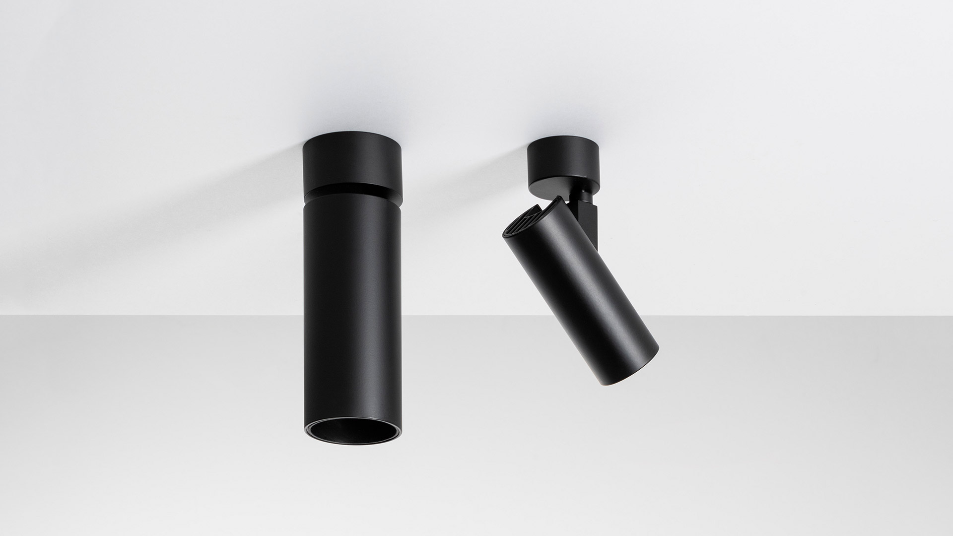 Two black Artemide Vector Ceiling spotlights mounted on white ceiling: left fixed vertical, right tilted at an angle