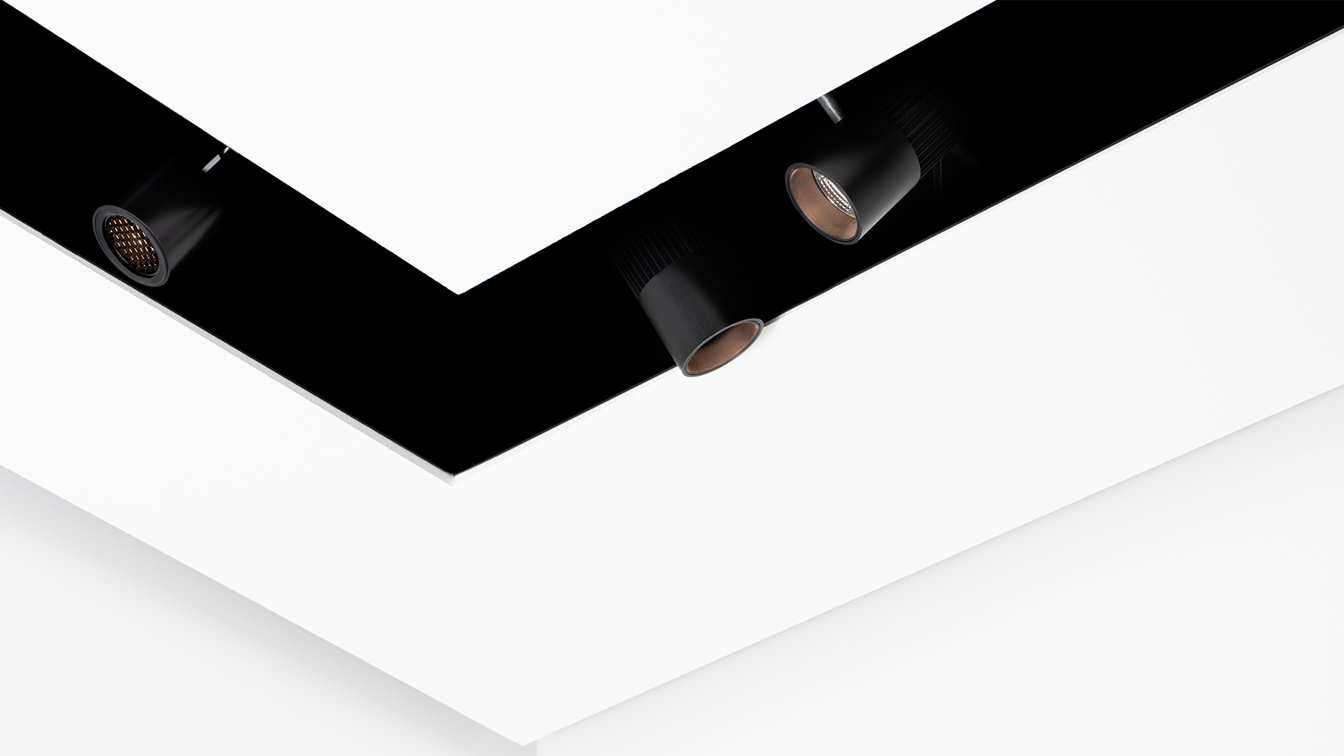 Three black recessed spotlights installed in a white ceiling corner, part of Artemide Vector Channel system