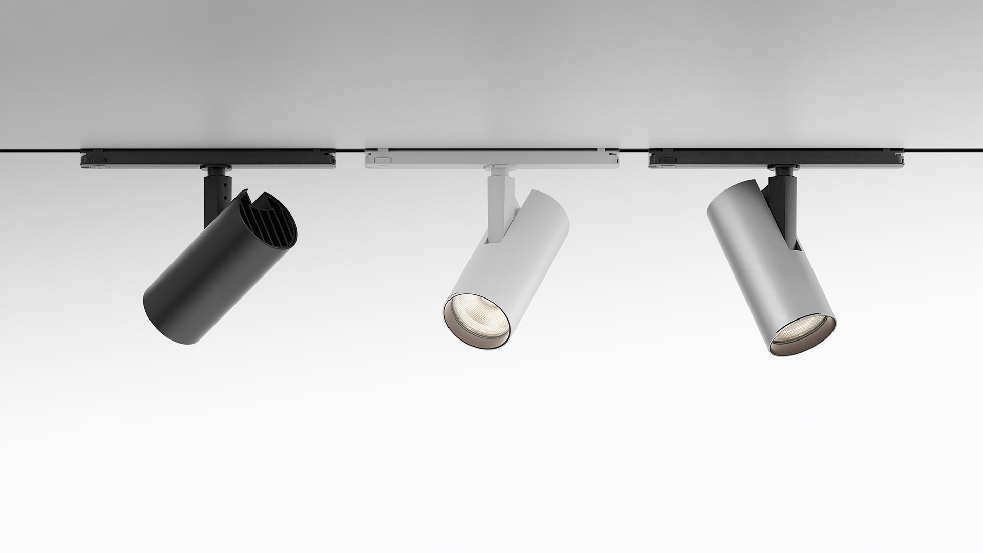 Three black Artemide Vector Track 230V spotlights in graduated sizes mounted on a black ceiling track, shown unlit
