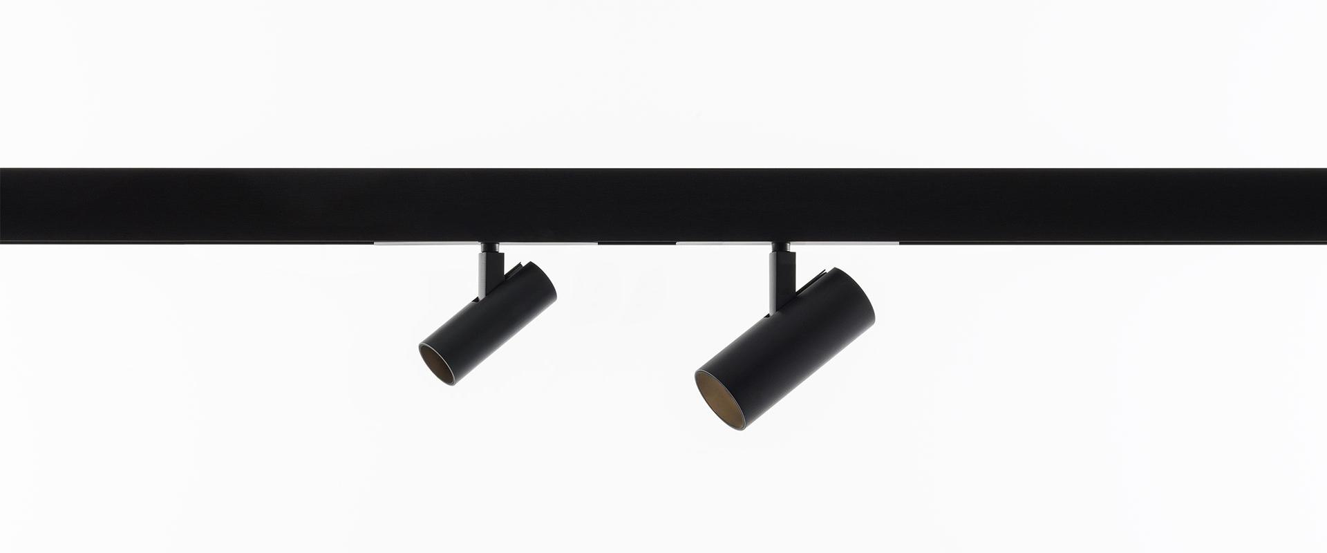 Two black cylindrical Artemide Vector Magnetic spotlights mounted on a black track rail, angled in different directions