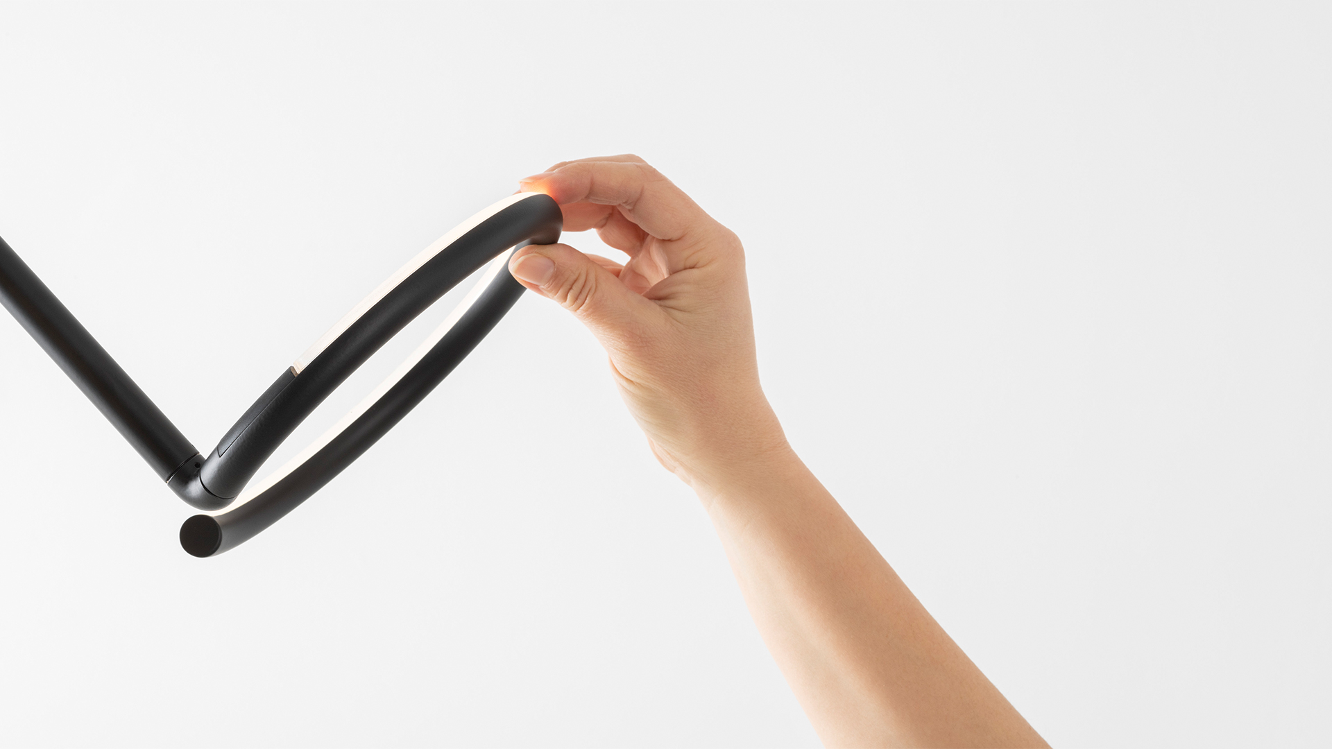 Artemide Vine Light table lamp: sinuous black tube forming a circular base, rising in angular steps, ending in a glowing circular LED ring