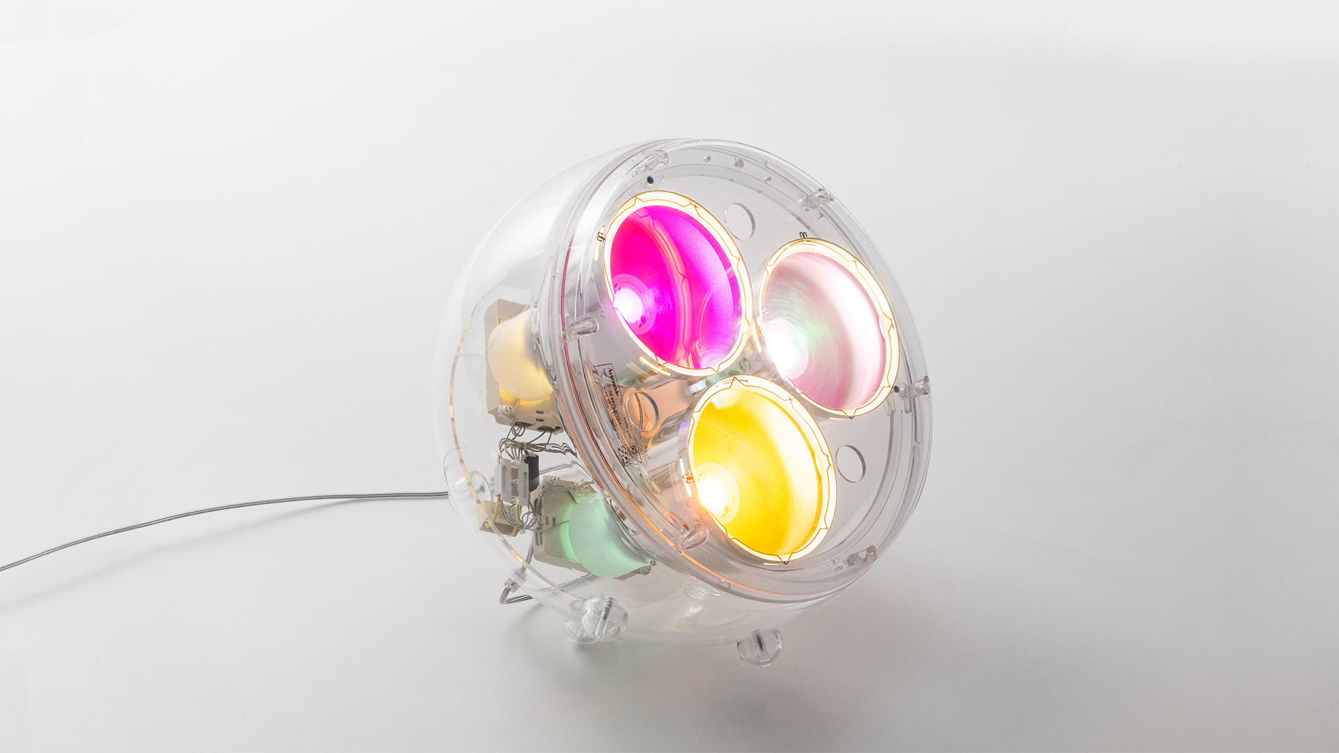 Artemide Yang-Yang LED table lamp: transparent spherical shell housing multiple colorful LED reflectors in pink, yellow, and white
