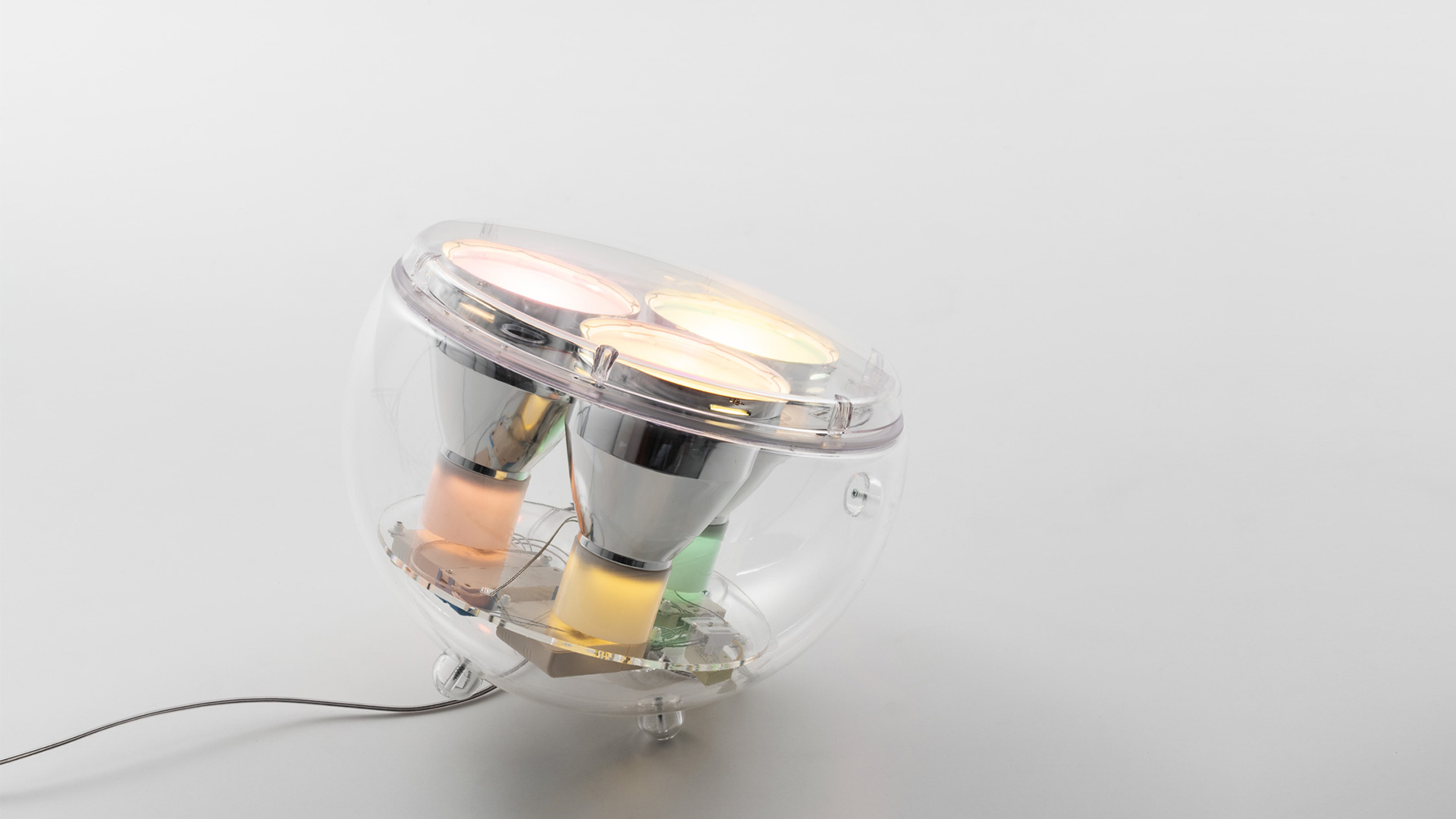 Artemide Yang LED lamp: transparent spherical globe revealing internal components—reflectors, circuit board, and warm LED light sources