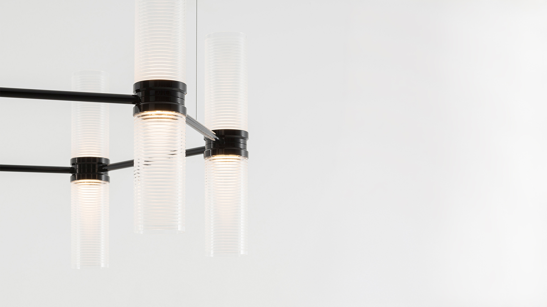 Artemide Zephyr chandelier with tiered cylindrical glass pendants illuminating a modern kitchen with high ceilings and wood cabinetry
